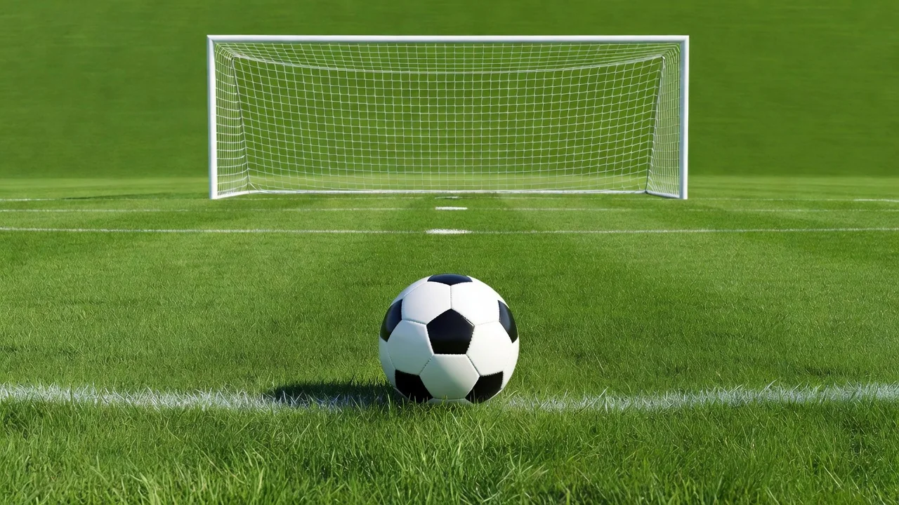 Soccer ball on the penalty spot facing an empty bright goal
